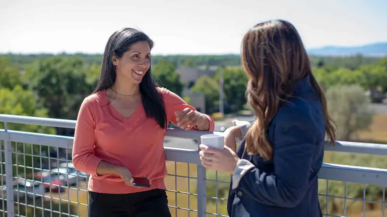 Two professionals talking on a building terrace above a leafy suburb, the kind of conversation that follows an old unreleased mortgage turning up in a chain