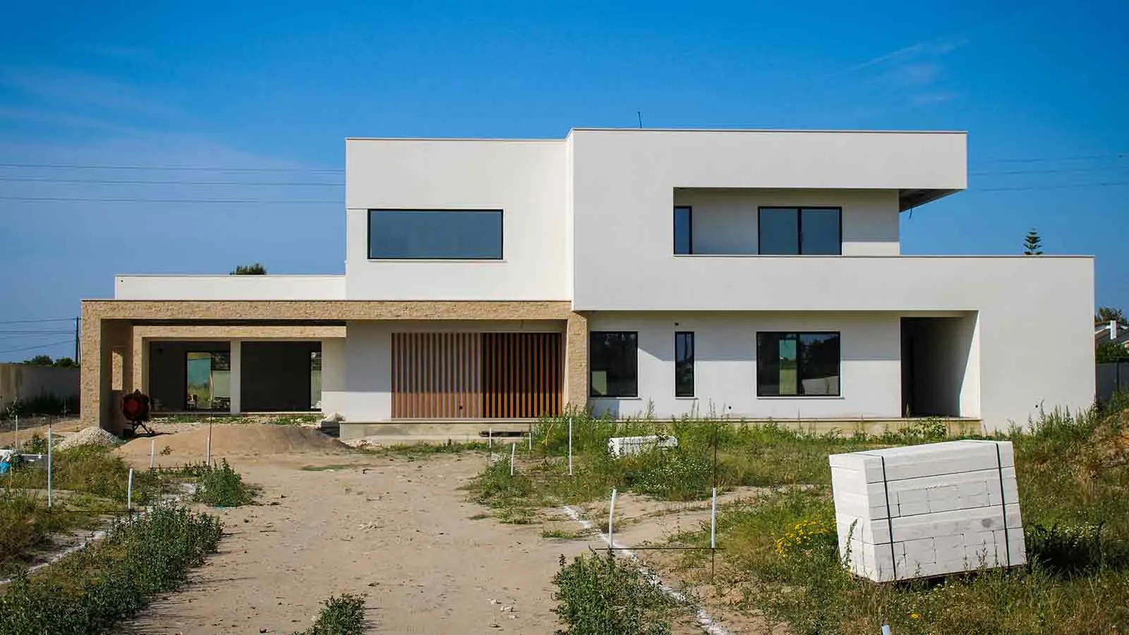 A newly built white house on an unlandscaped lot with survey stakes still in the ground, a reminder that a parcel’s identity has to be established before its chain can be